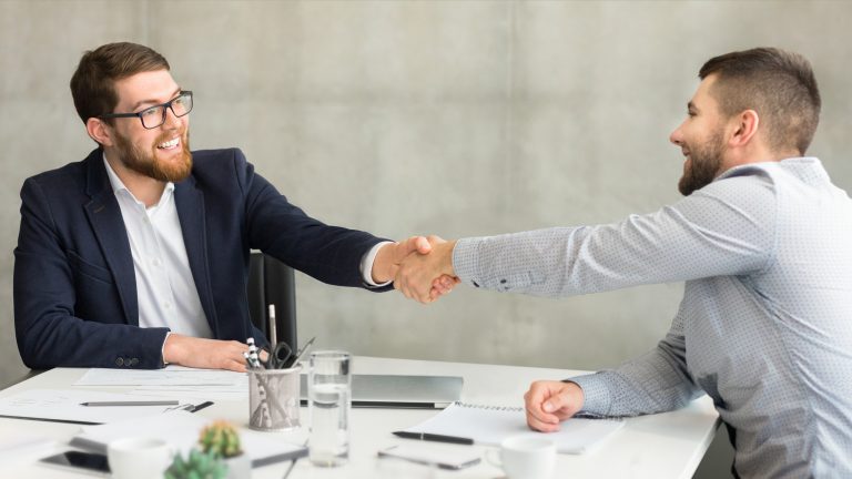 Businessmen shaking hands in office setting, successful deal